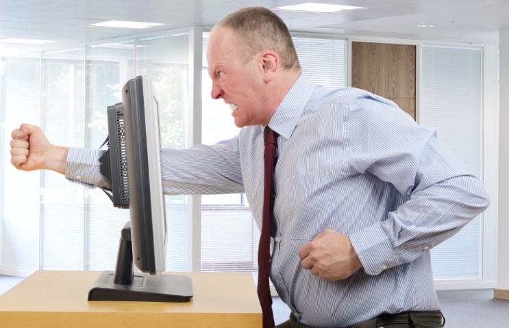 Businessman in office in a rage with a computer screen